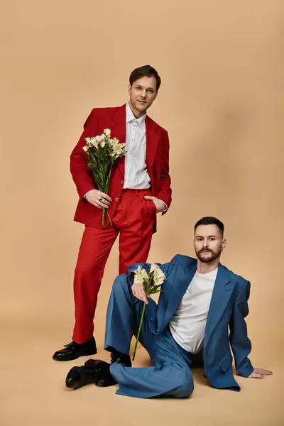 Two men in elegant suits pose for a portrait, one holding white flowers. — Stock Photo
