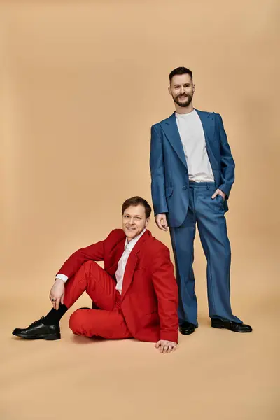 Two men in suits pose for a photograph, one standing and one sitting. — Stock Photo