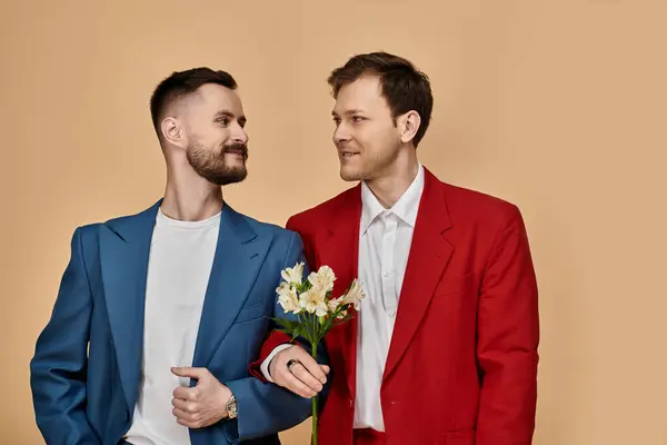 Two men in stylish suits look lovingly at each other against a soft background. — Stock Photo