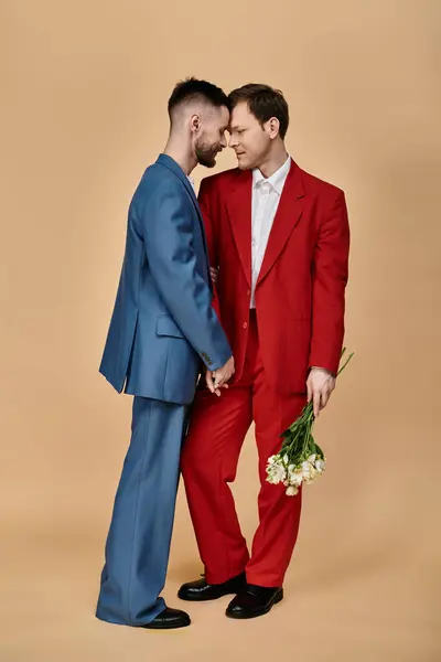 Dos hombres vestidos de traje se paran cerca, mirándose amorosamente. - foto de stock