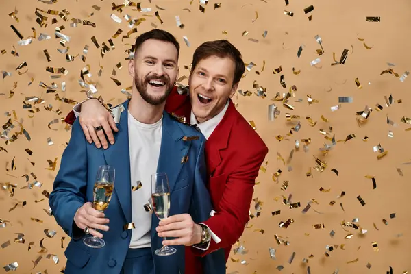 Two men in elegant suits celebrate with champagne and confetti. — Stock Photo