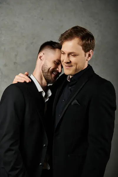 Um casal gay amoroso, ambos em ternos pretos elegantes, compartilham um momento terno com um abraço caloroso. — Fotografia de Stock