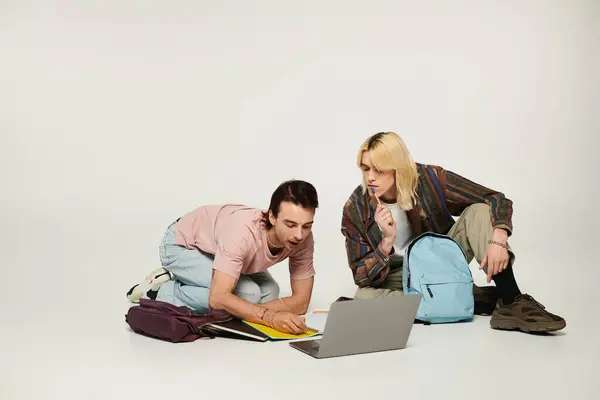 Dois jovens estudantes em trajes casuais estão estudando juntos, focando em um laptop na frente deles. — Fotografia de Stock