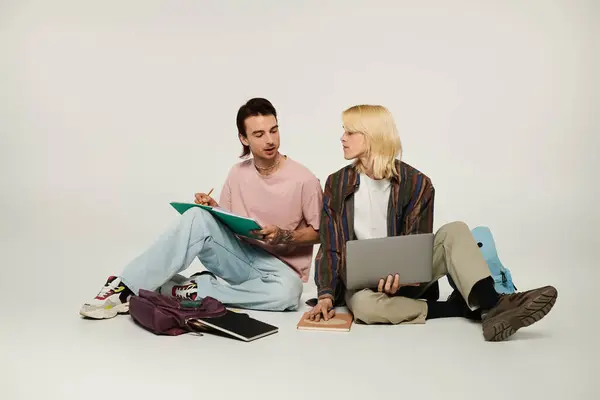 Dos jóvenes estudiantes queer están sentados en el suelo, estudiando juntos. — Stock Photo