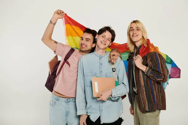 Tres jóvenes estudiantes queer con atuendo casual posan con una bandera de orgullo. — Stock Photo