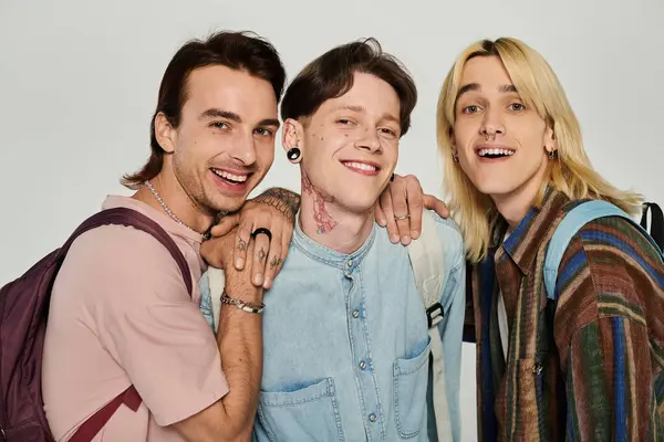 Three young students from the queer community smile together in casual attire against a grey background. — Stock Photo