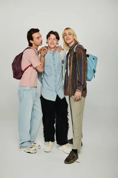 Three young people, members of the LGBTQIA community, stand together in casual attire against a grey background. — Stock Photo