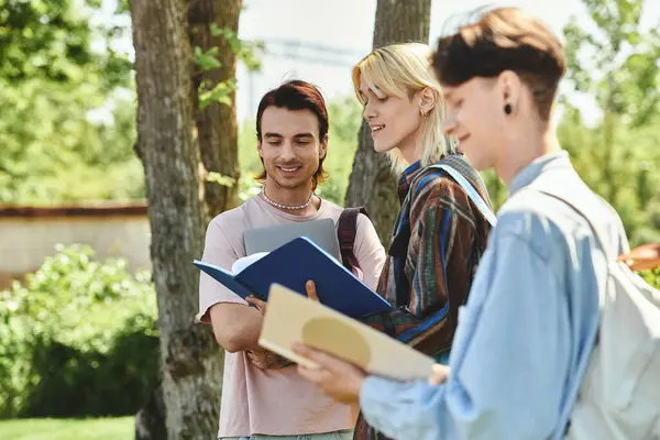 Three young friends, dressed casually, study together outside on a sunny day. — Stock Photo