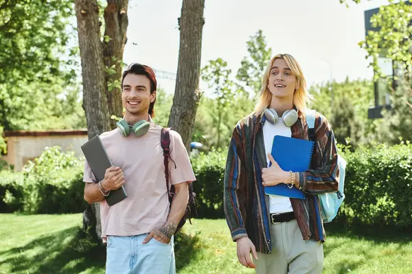 Two young friends walk together through a college campus, enjoying a sunny day. — Stock Photo