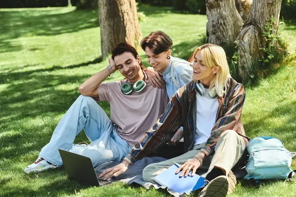 Three young queer friends laugh together in a park on a sunny day. — Stock Photo