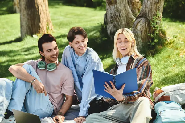 Three young friends, dressed casually, share a laugh while reading a book outdoors. — Stock Photo