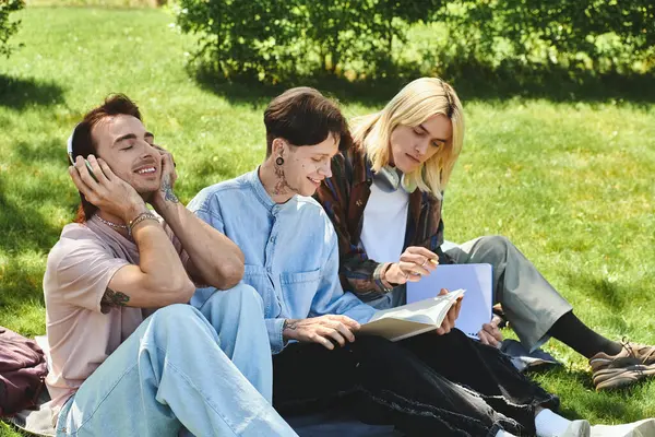 Three young friends enjoy a sunny afternoon outdoors, one listening to music while the others read. — Stock Photo