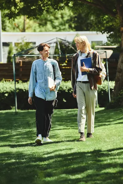 Two young friends walk side-by-side in a green park, enjoying the sun and each others company. — Stock Photo