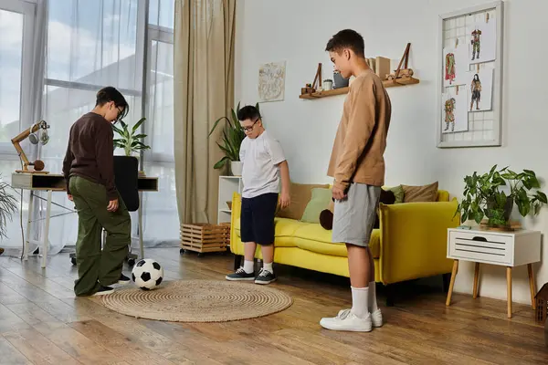 Three young boys playing soccer inside a home. — Stock Photo