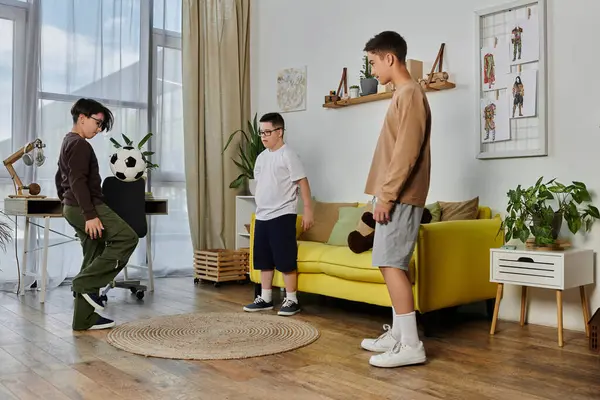 Tres chicos juegan al fútbol adentro, con un chico haciendo malabares con la pelota. — Stock Photo