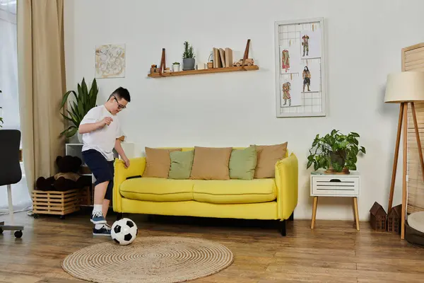 A young boy with Down syndrome plays soccer indoors with his friends. — Stock Photo