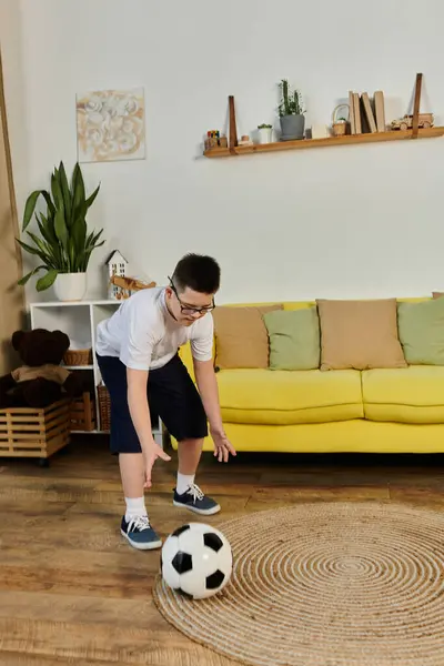 A young boy with Down syndrome plays soccer indoors with his friends. — Stock Photo