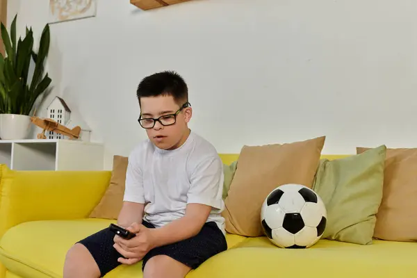 A boy with Down syndrome enjoys time with friends, soccer ball, and smartphone at home. — Stock Photo