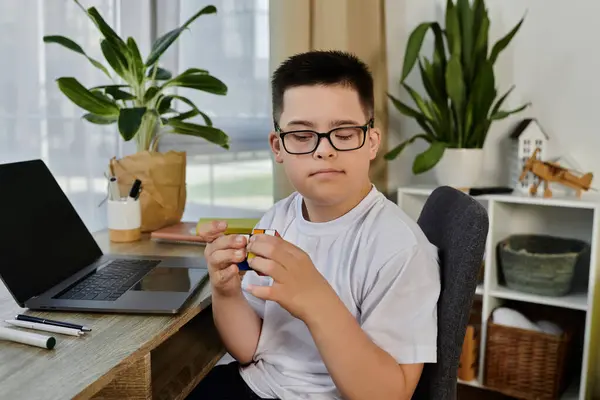 A young boy with Down syndrome concentrates on solving a puzzle while sitting at his desk at home. — Stock Photo