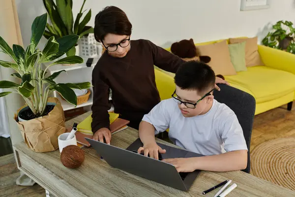 Two young boys, one with Down syndrome, work together on a laptop. — Stock Photo