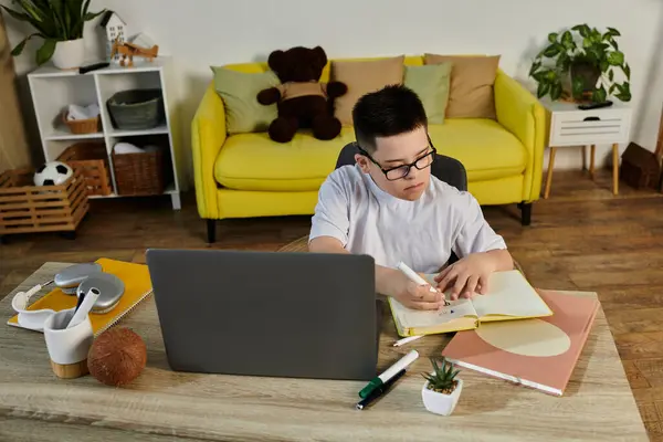 A young boy with Down syndrome studies at home. — Stock Photo