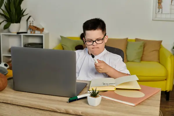 A young boy with Down syndrome studies at home, intently focused on his work. — Stock Photo