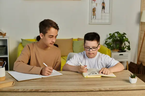 Zwei Jungen sitzen an einem Tisch und schreiben in Notizbücher. — Stockfoto