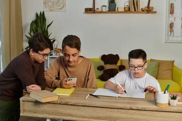 Three young boys are working on schoolwork at a table in a home. — Stock Photo