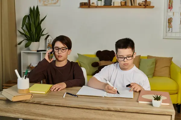 Deux jeunes garçons, l'un avec le syndrome de Down, sont assis à une table faisant leurs devoirs. — Photo de stock