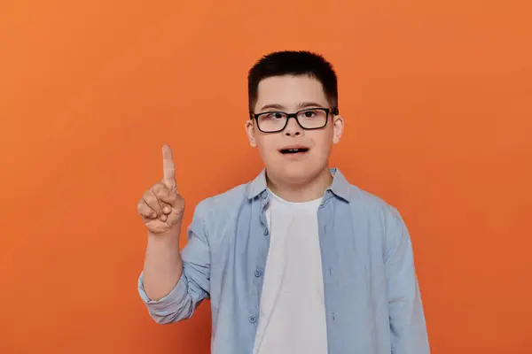 Un ragazzo con la sindrome di Down punta il dito verso l'alto, esprimendo un pensiero o un'idea. — Foto stock