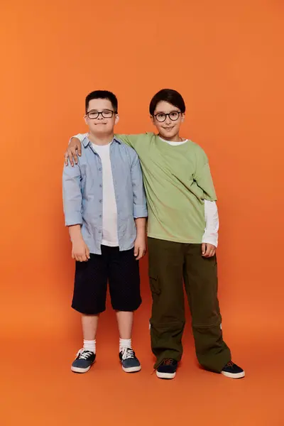 Two young boys with arms around each other, orange background. — Stock Photo