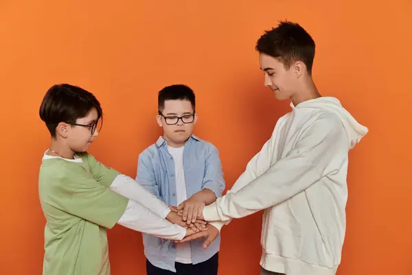 Three young boys, one with Down syndrome, stack hands. — Stock Photo