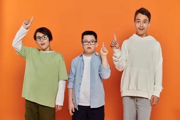 Three boys stand together, pointing upwards in a gesture of unity and optimism. — Stock Photo