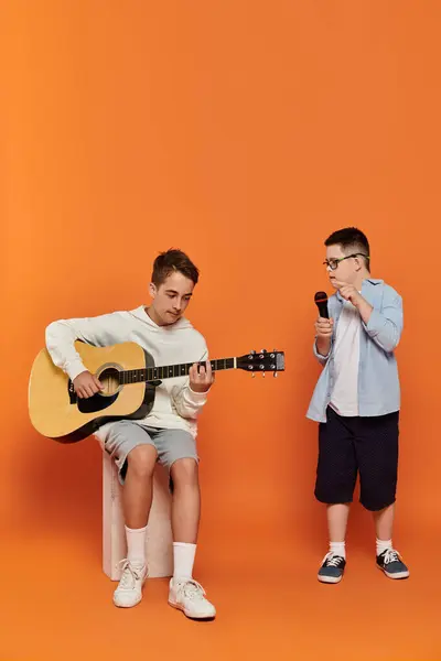Deux garçons ayant un moment musical : l'un à la guitare, l'autre chantant dans un micro. — Photo de stock