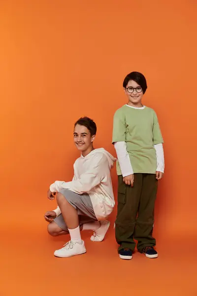 Two boys stand in front of an orange background. — Stock Photo