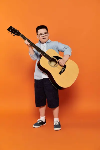 A young boy plays an acoustic guitar in a home setting. — Stock Photo