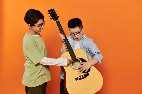 Two young boys play a guitar together at home. — Stock Photo
