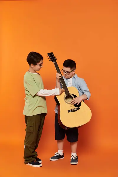Dois meninos, um com síndrome de Down, tocam guitarra juntos em um ambiente doméstico. — Fotografia de Stock