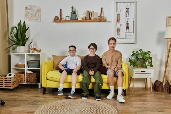 Tre giovani ragazzi siedono insieme su un divano giallo, sorridendo. — Foto stock