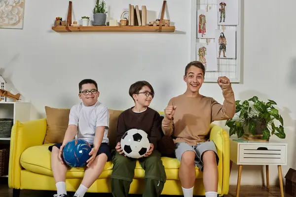 Three boys sitting on a yellow couch, cheering for their favorite team. — Stock Photo