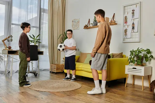 Три мальчика играют с футбольным мячом в гостиной. — стоковое фото
