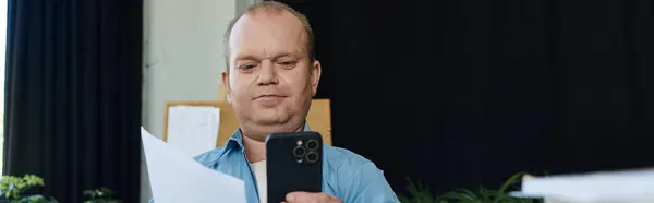 A man with inclusivity examines documents while holding his phone. — Stock Photo