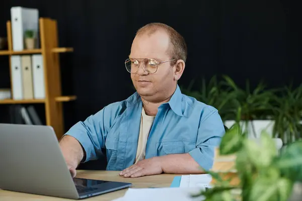 Ein Mann mit Brille arbeitet fleißig an einem Laptop an seinem Schreibtisch im Büro. — Stockfoto