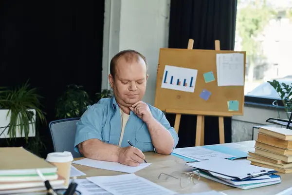 A man with inclusivity sits at a desk in an office, focused on his work. — Stock Photo