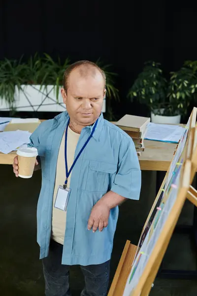 A man with inclusivity stands near a whiteboard, holding a cup of coffee. — Stock Photo