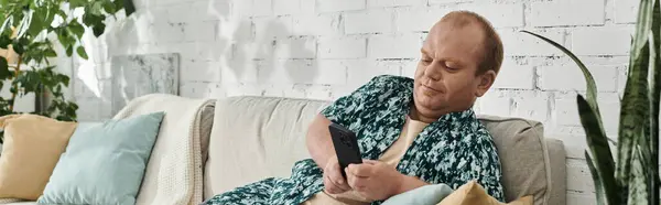 Un uomo con inclusività si rilassa su un divano nel suo salotto, scorrendo il suo telefono. — Foto stock