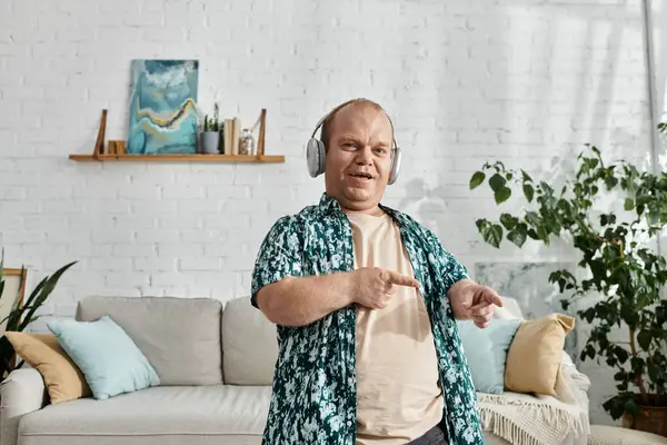 A man with inclusivity with headphones dances enthusiastically in a living room setting. — Stock Photo