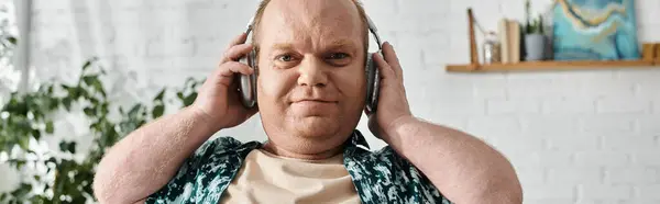 A man with inclusivity wearing headphones is sitting in his living room and enjoying music. — Stock Photo