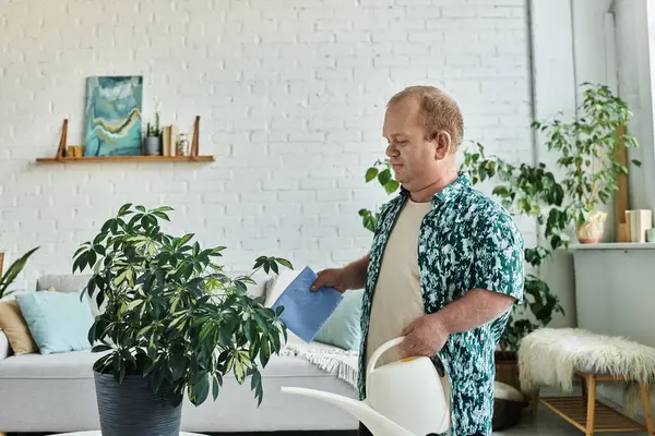 A man with inclusivity in a patterned shirt waters plants in a modern home with white brick walls. — Stock Photo