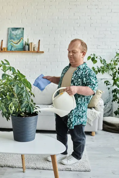 A man with inclusivity waters a plant in a modern living room. — Stock Photo